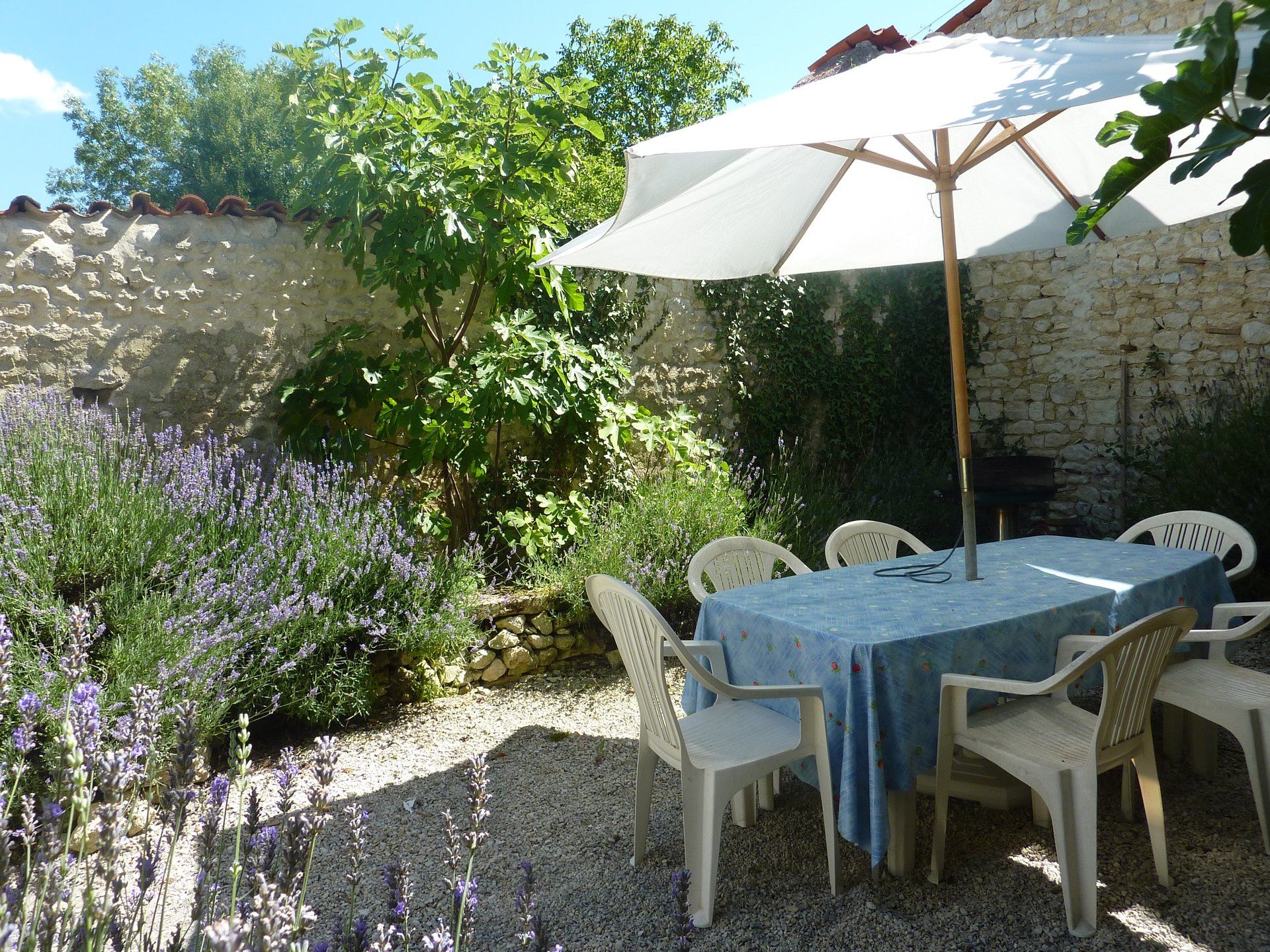 plastic garden table with pale blue tablecloth and large parasol