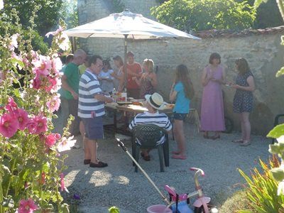 group of adults stood chatting in the sunshine around a garden table