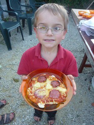 A young boy showing the cooked pizza he made