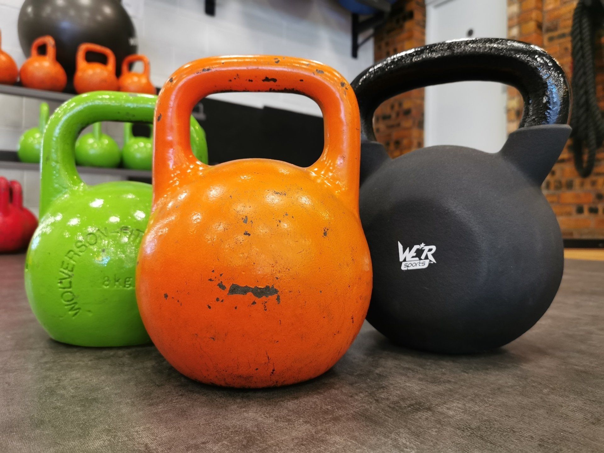 Personal Training - Image of a trio of bell weights, orange, green and black