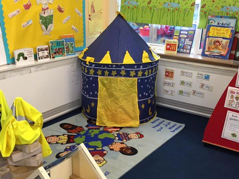 A reading area in the corner of a room with a blue and yellow play tent
