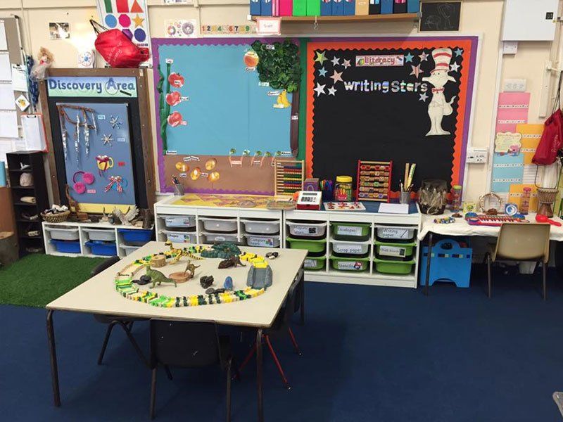 A small square desk in a nursery with toys on top of it