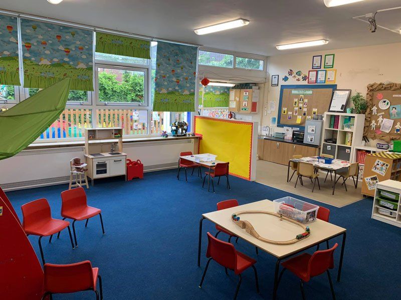 A nursery with blue carpet and red chairs around small tables