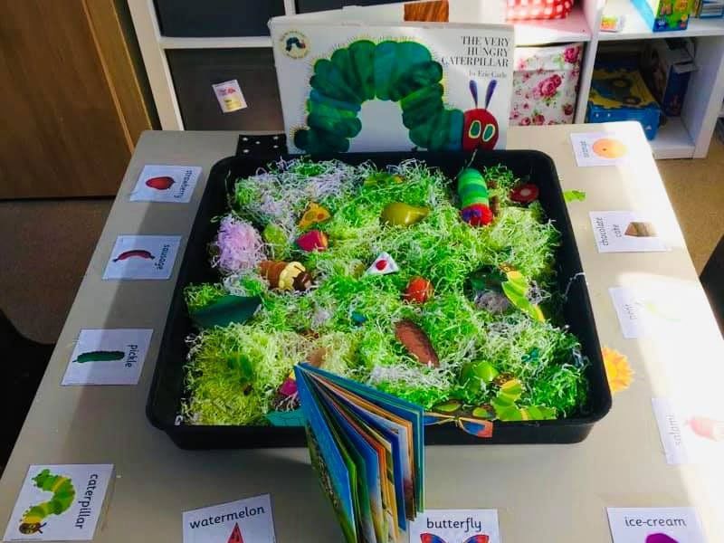 A display about insects including books, picture cards, and plastic figures in artificial green grass