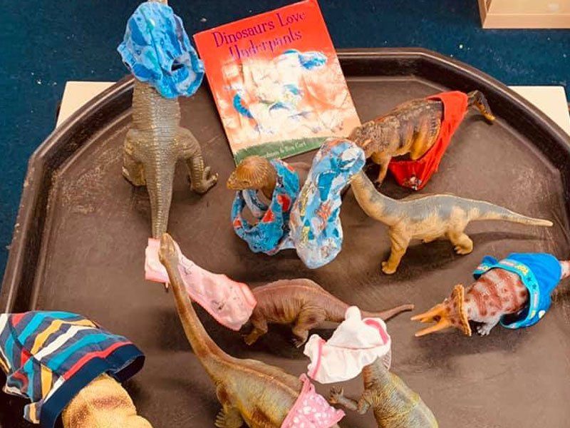 Various plastic dinosaur figures with underwear on their heads
