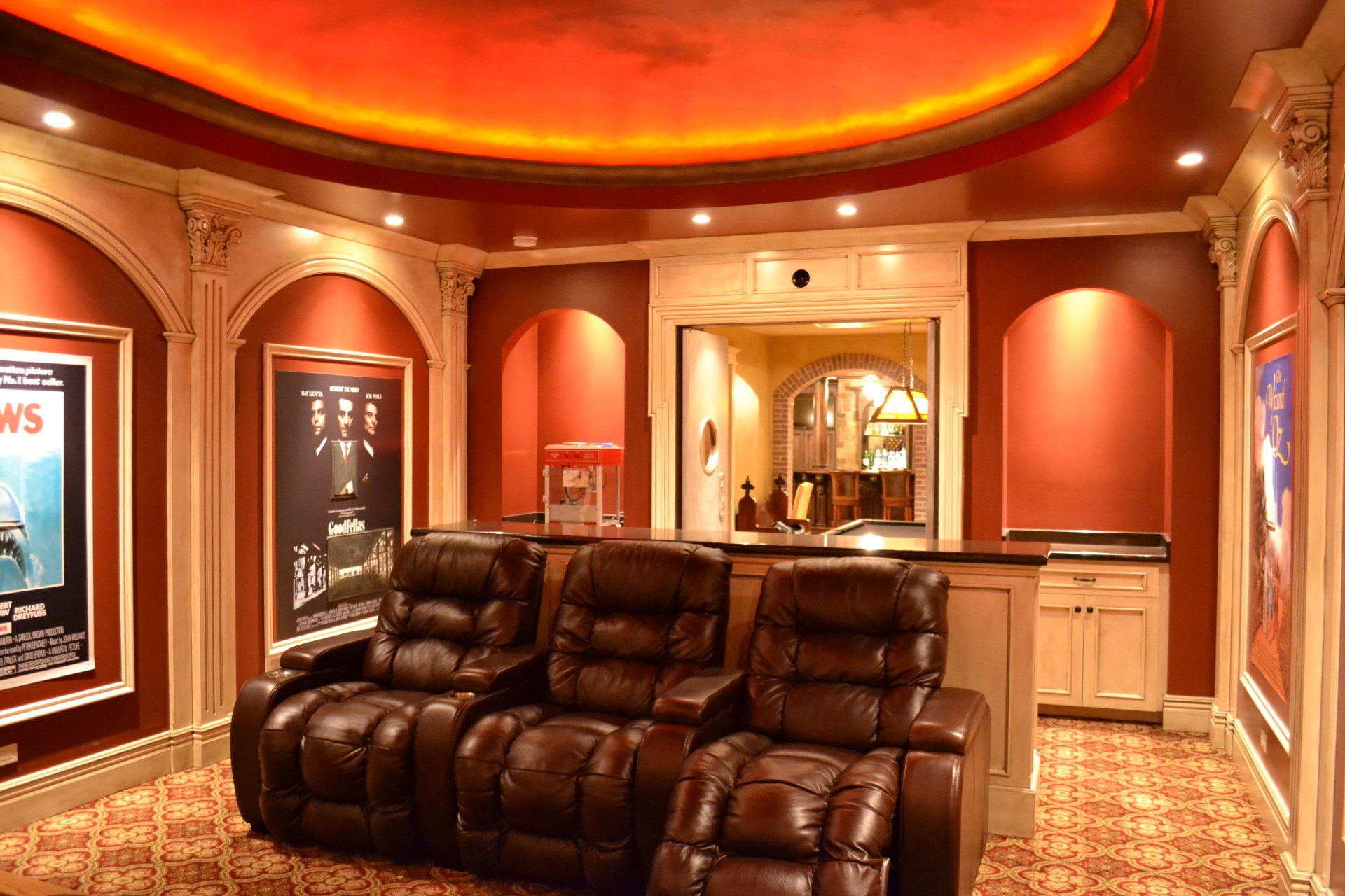 Home theater with reclining leather seats, red walls, and movie posters.