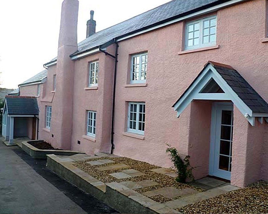 The exterior of a row of terraced houses, pink walls with blue doors