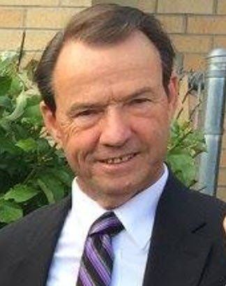 A man in a suit and tie is smiling for the camera.