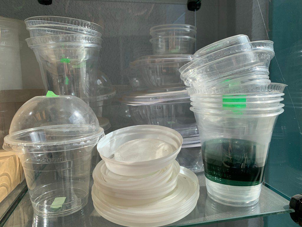 A shelf filled with lots of bioplastic cups and plates.