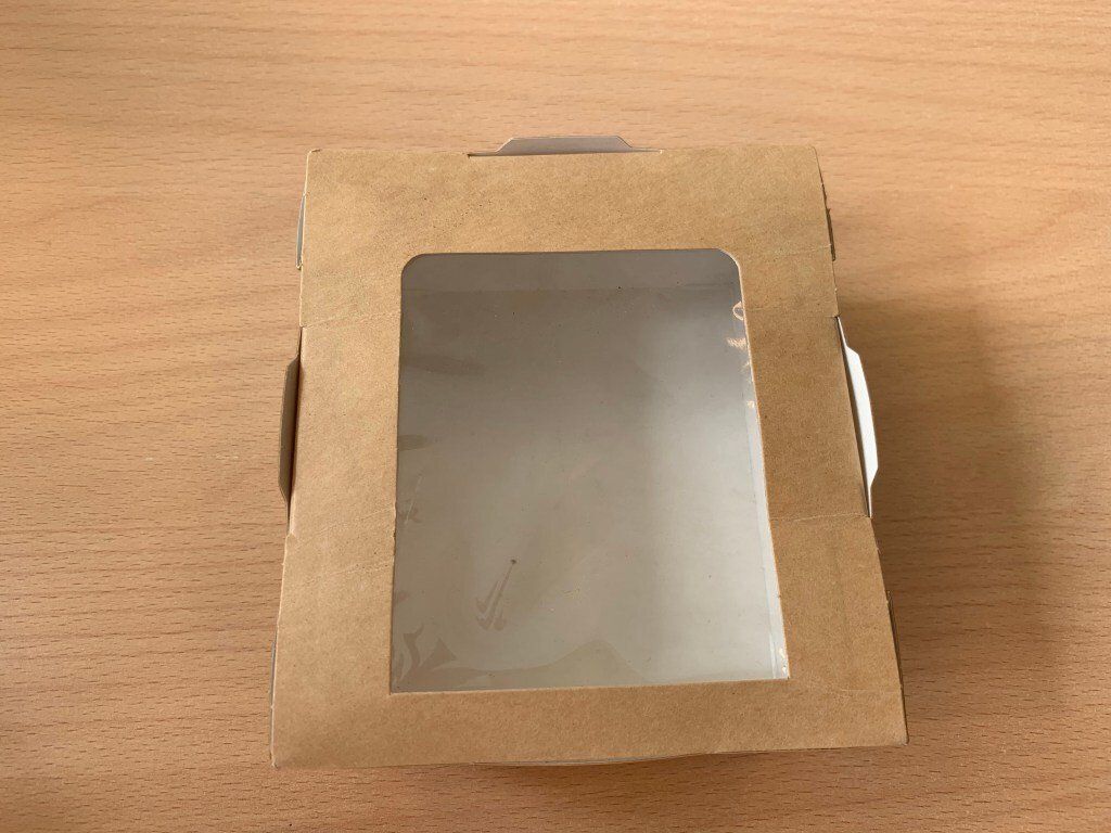 A brown box with a clear window is sitting on a wooden table.