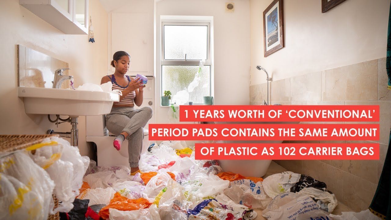 A woman is sitting in a bathroom surrounded by plastic bags.