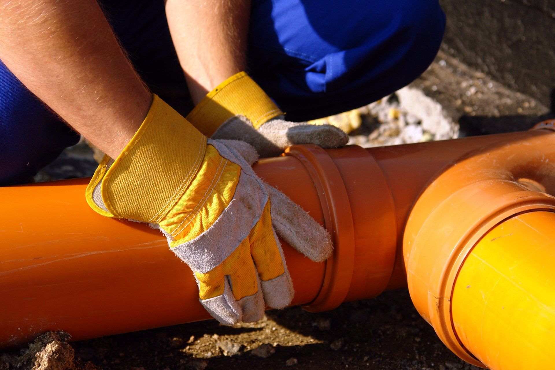 loseup of plumber's hands assembling pvc sewage pipes in house foundation