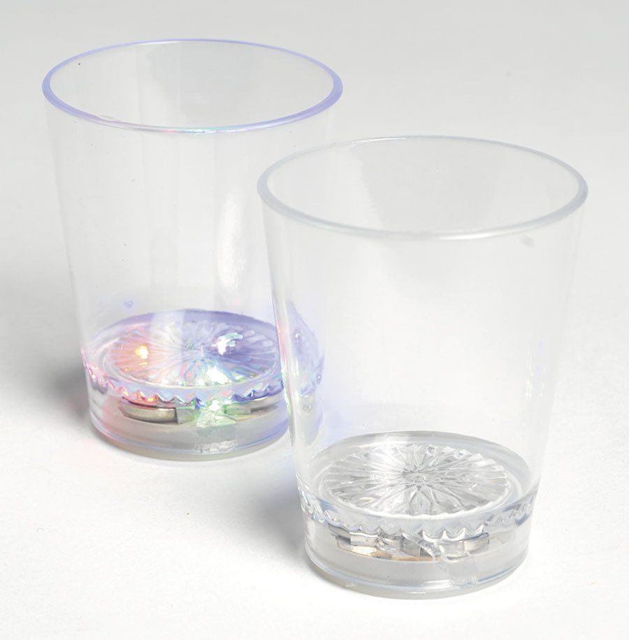 Two clear glasses with lights inside of them are sitting on a table.