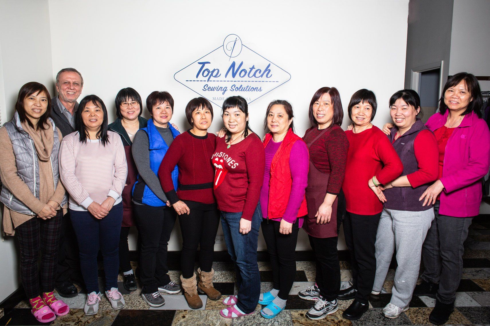 A group of women are posing for a picture in front of a sign that says top notch.