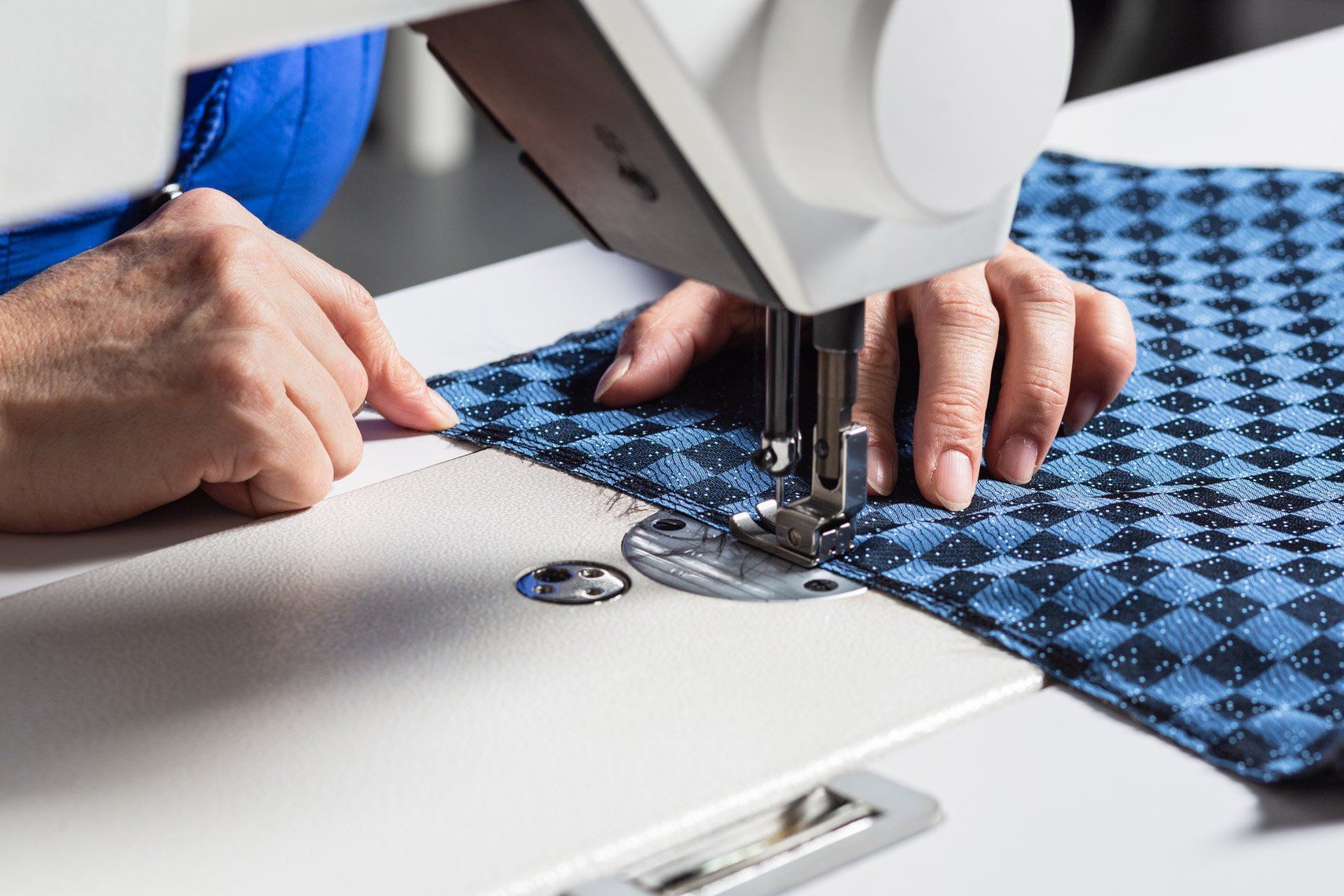 A person is using a sewing machine to sew a piece of fabric.