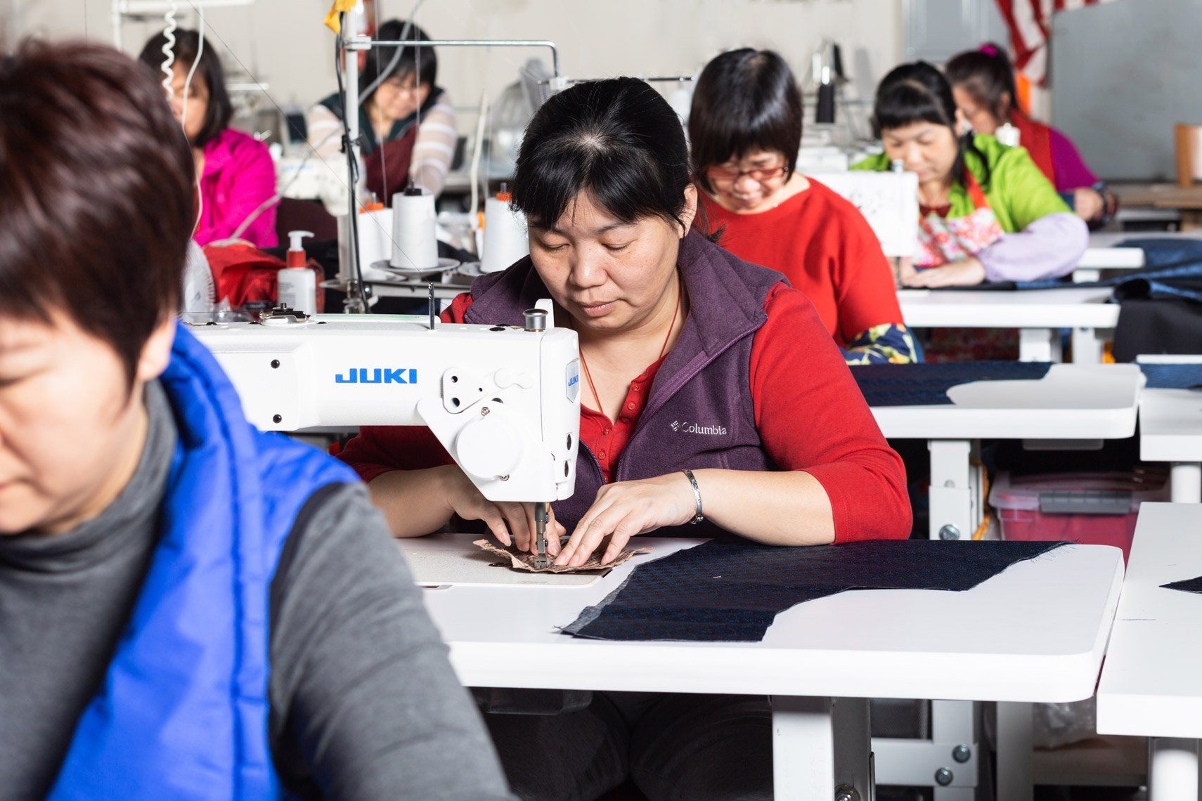 A woman is using a juki sewing machine in a factory
