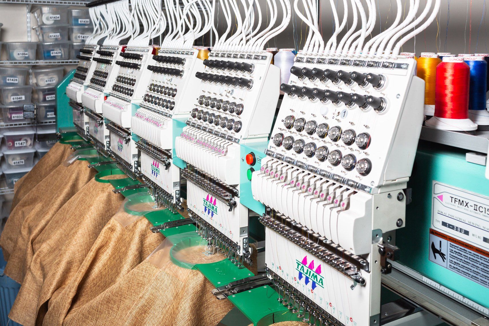 A row of embroidery machines are sitting next to each other in a room.