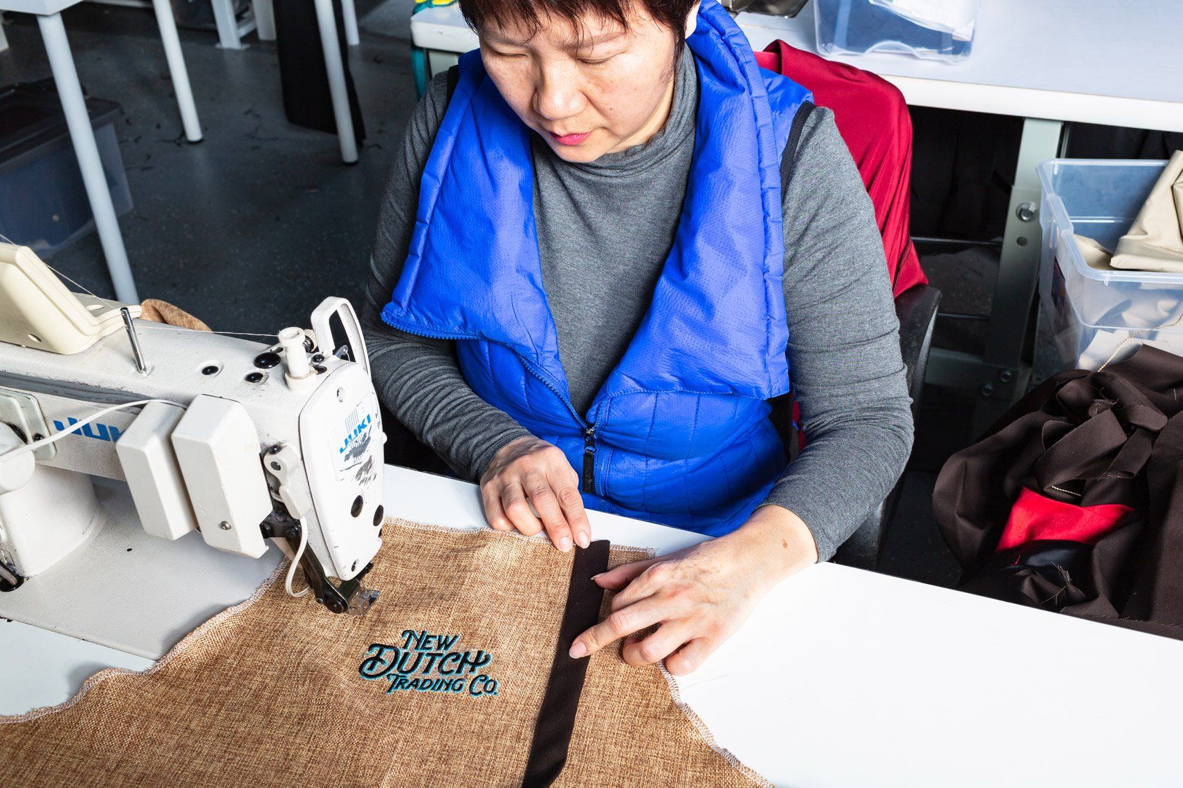 A woman is sitting at a table using a sewing machine.