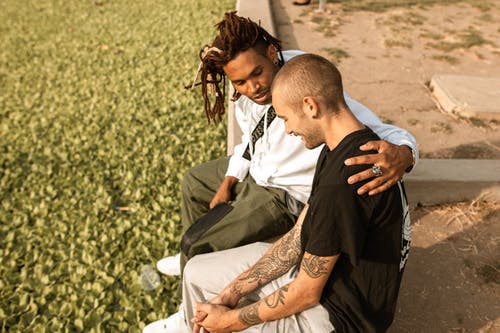 two men sitting one consoling other sad talk