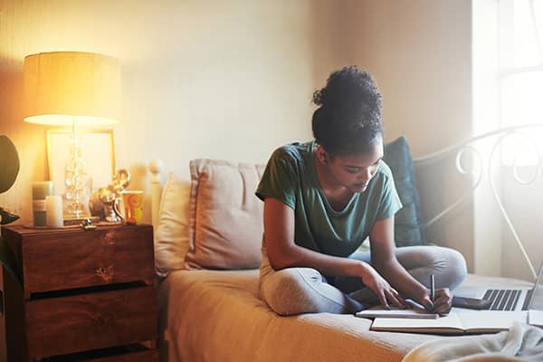 Student doing homework on her bed