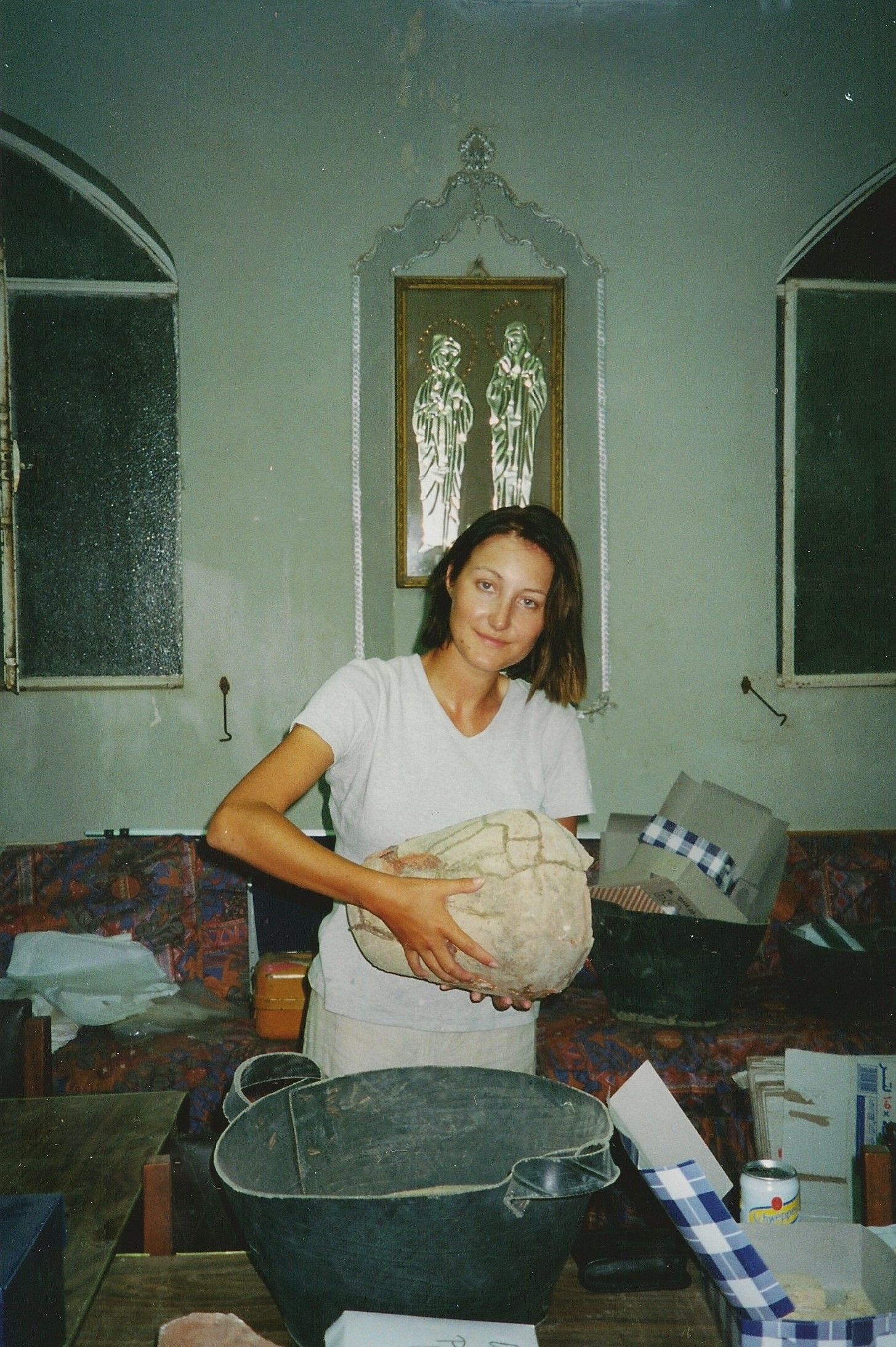 Een vrouw staat in een keuken beslag te mengen, achter een tafel met kommen en keukengerei.