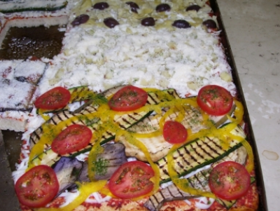 una pizza in teglia pronta da infornare con melanzane peperoni, pomodori e mozzarella