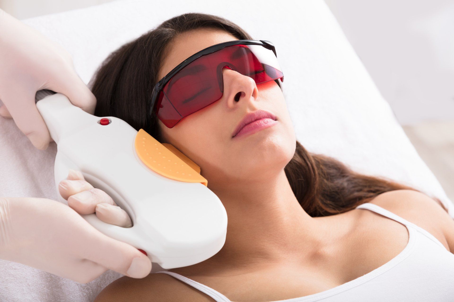 professional performing laser skin therpy on young patient