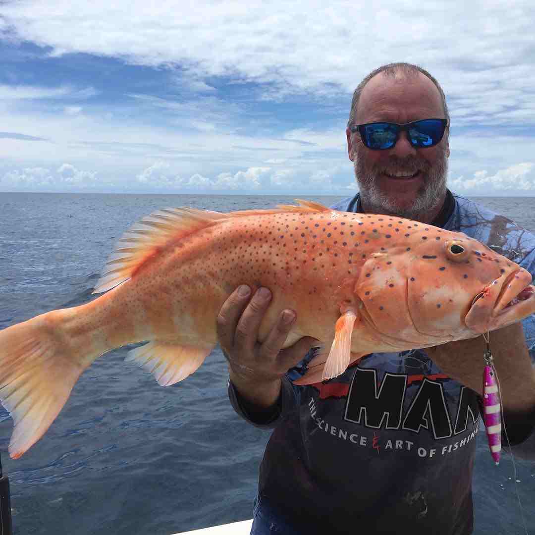 man holding an orange fish — Fishing apparel Yeppoon in Yeppoon, QLD