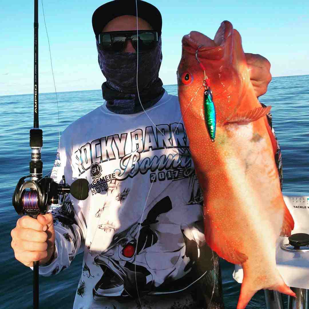man holding a fishing rod and an orange fish — Fishing apparel Yeppoon in Yeppoon, QLD