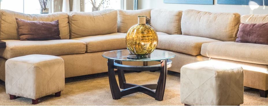 beige carpet and couch with endtable and ottomans