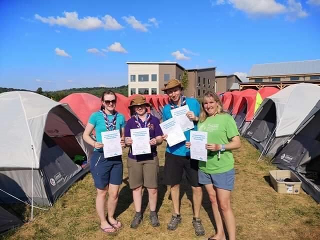 A group of people standing in front of tents holding papers