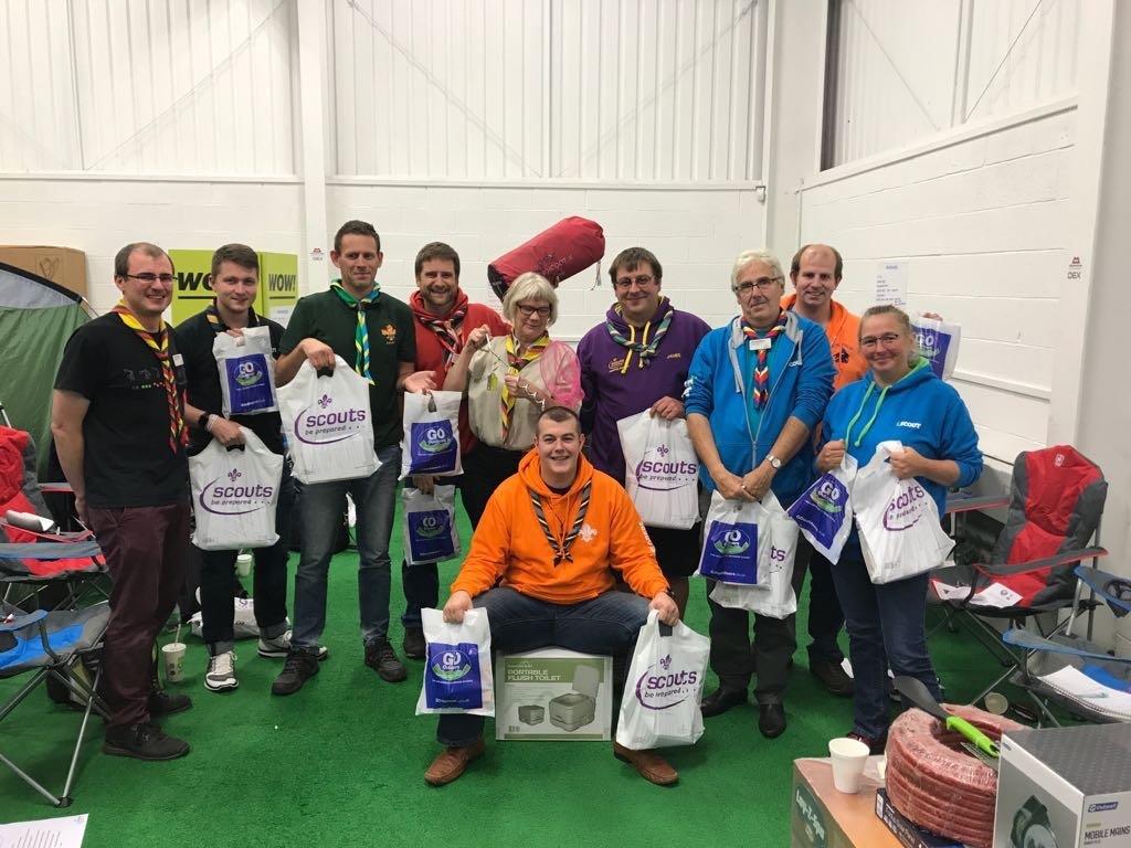 A group of people are posing for a picture in a room holding bags.