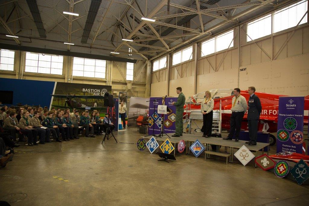 A group of people are standing on a stage in a large room.