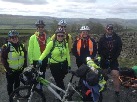 A group of people standing next to bicycles on a road.