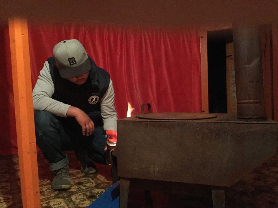 man steekt houtkachel aan in een mongoolse gers