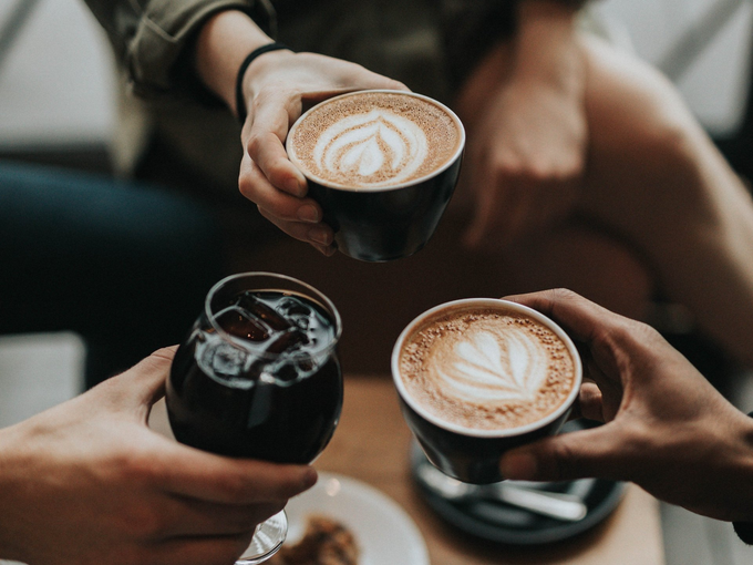 A group of people are toasting with three cups of coffee.