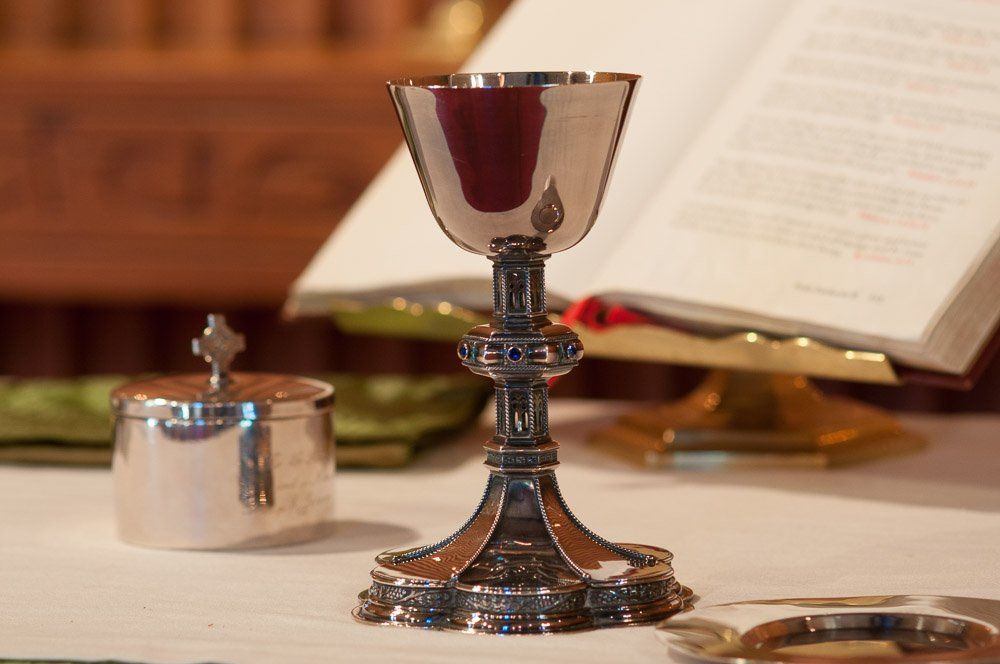 a silver chalice sits on a table in front of an open bible