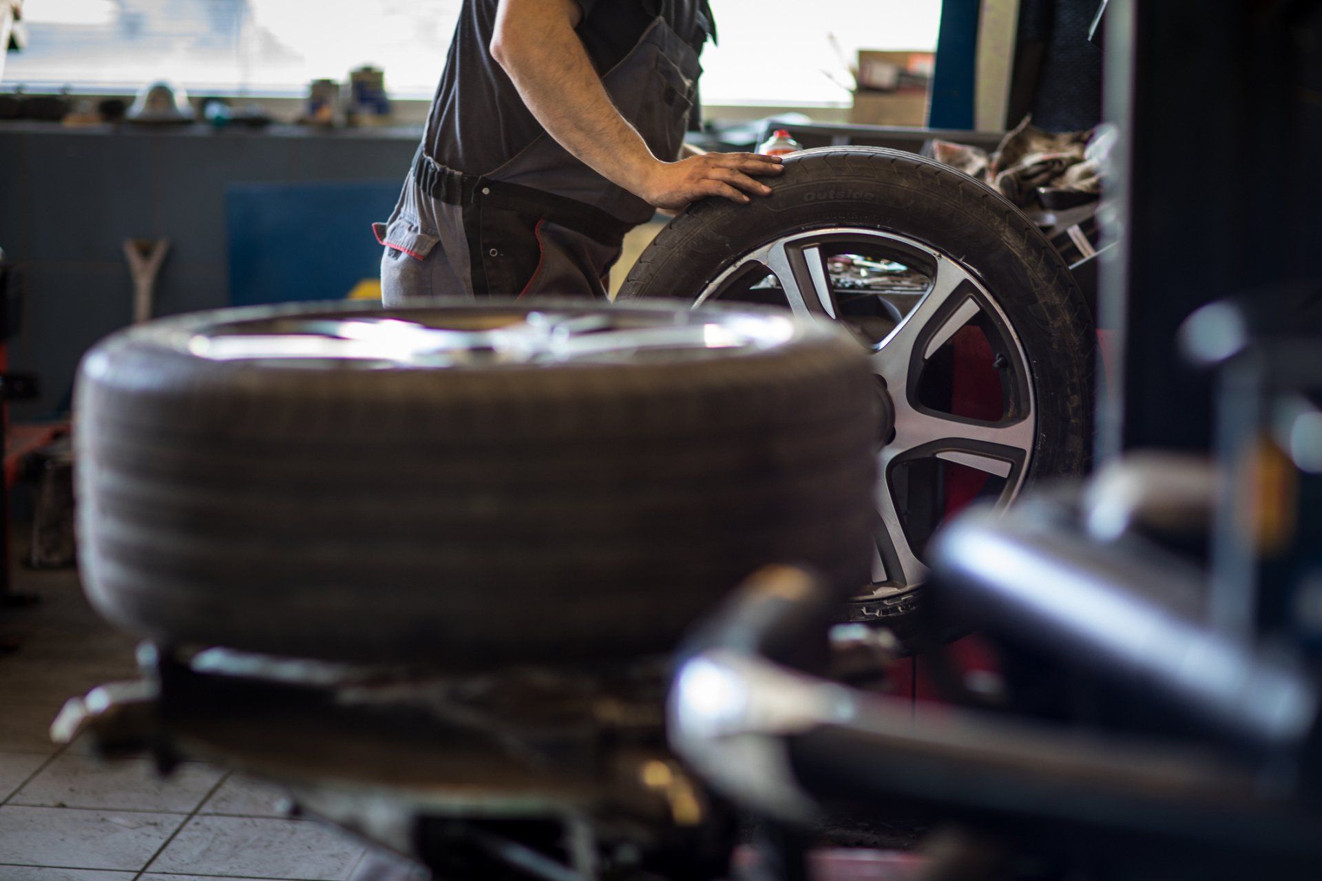 Mechanic in a garage with tires and equipment.