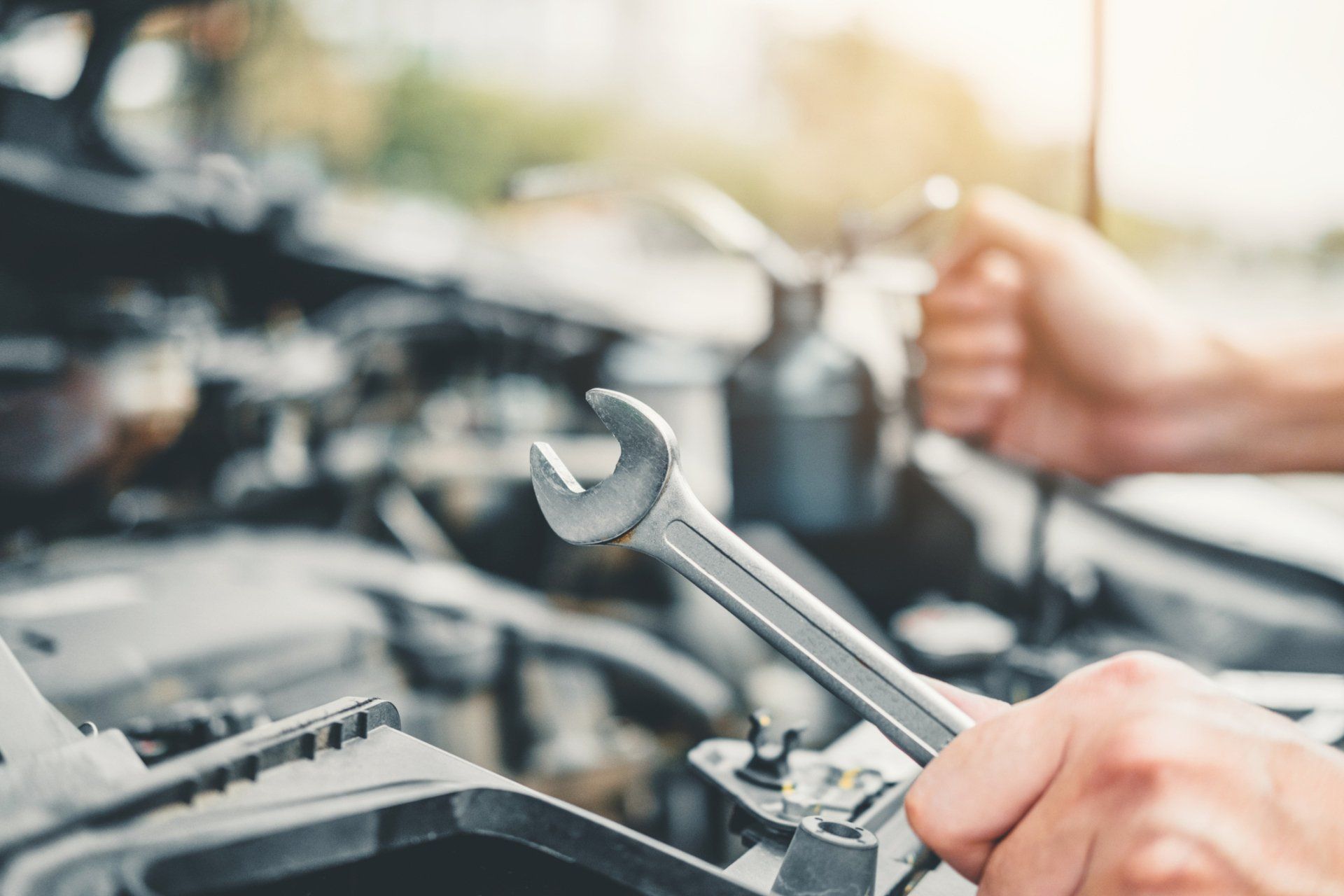 Person holding a wrench, working on a car engine.