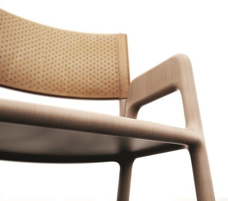 Primo piano di una sedia in legno chiaro con schienale e braccioli traforati color cuoio su sfondo bianco.