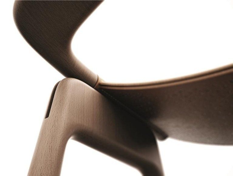 Primo piano di una sedia di legno marrone con sedile e schienale curvi su sfondo bianco.