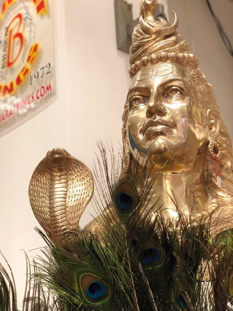 Een gouden beeld van een vrouw met pauwenveren en een cobra