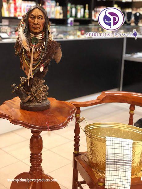 Een standbeeld van een Indiaan zit op een houten tafel naast een stoel.