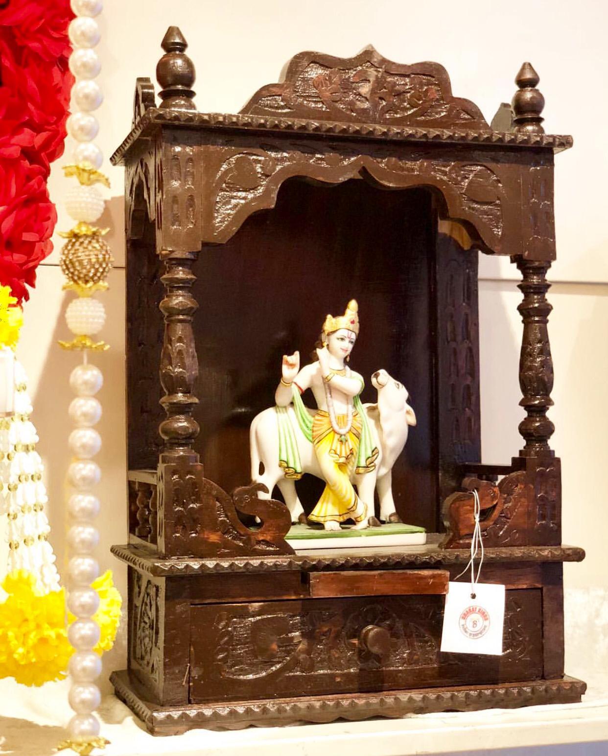 Een houten tempel met een beeld van Krishna op een koe