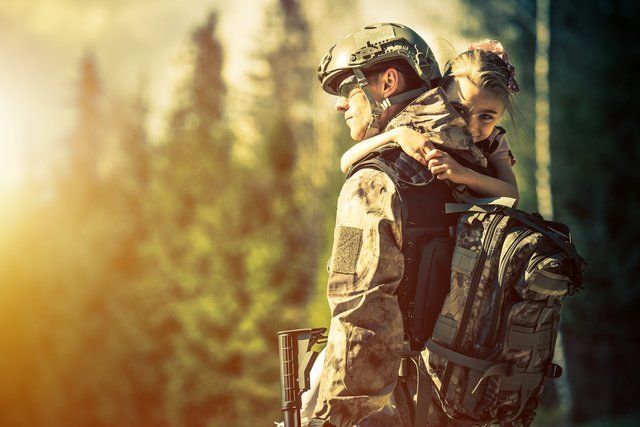 A soldier is carrying a small child on his back.