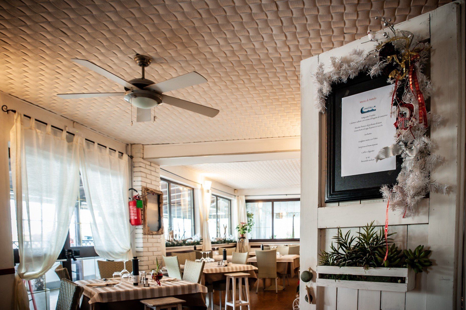 Un ristorante con tavoli e sedie e un ventilatore a soffitto