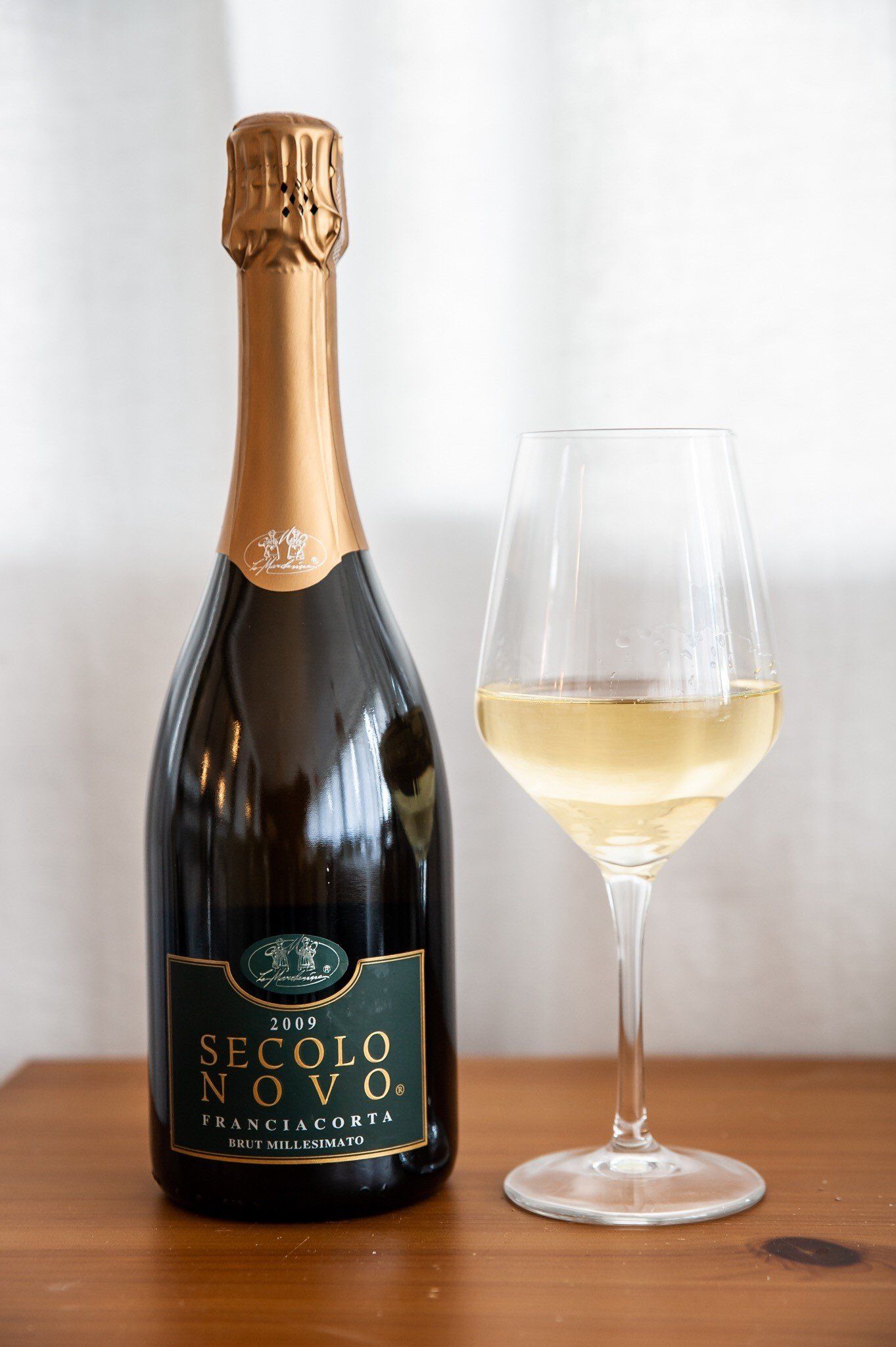 Una bottiglia di champagne e un bicchiere di vino sono su un tavolo di legno.
