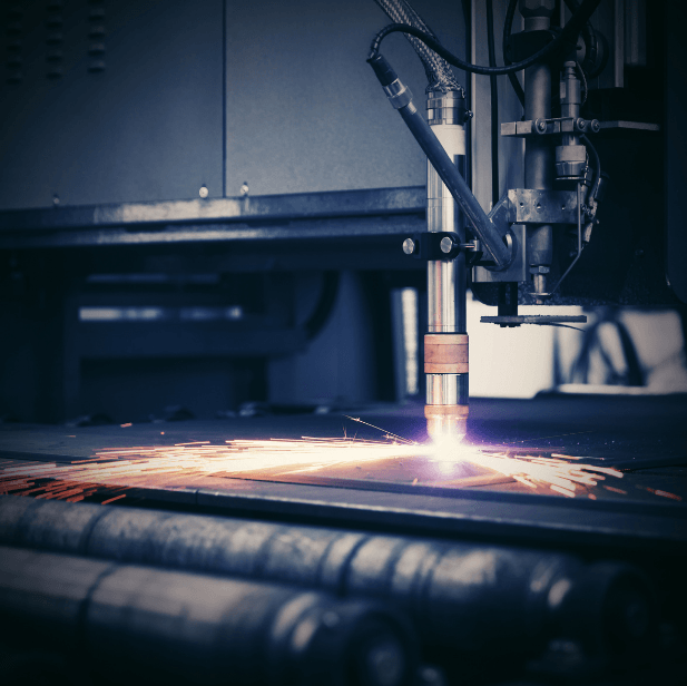 Industrial laser cutter cutting metal, bright sparks flying in a dark workshop.