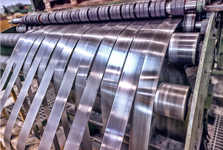 Industrial steel slitting machine unwinding shiny metal strips in a factory