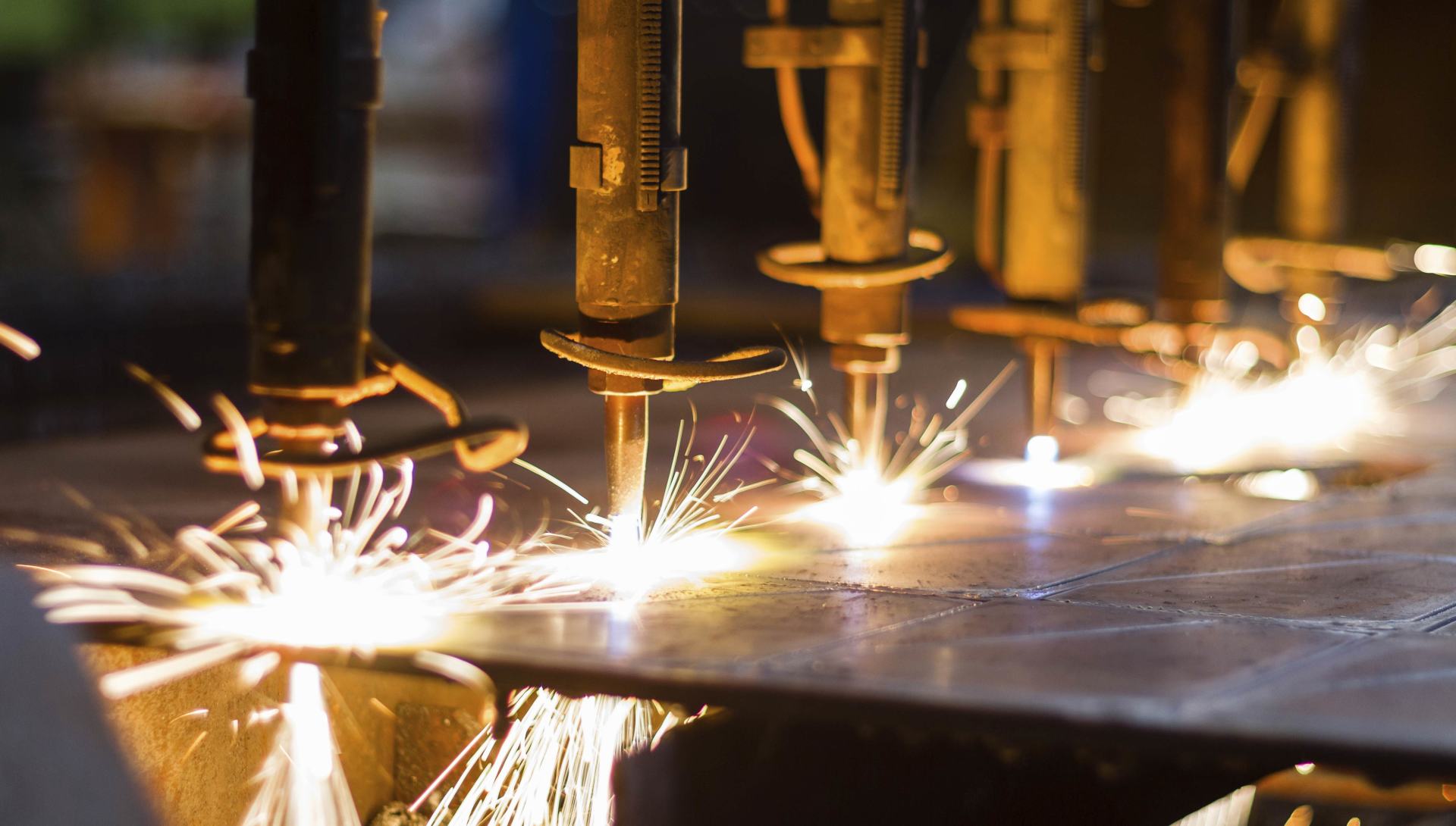 Industrial laser cutting metal, with bright sparks flying in a factory setting